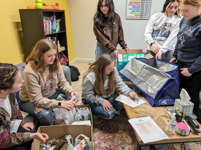 HDFS club members take inventory and organize items at Hello Neighbor during the process of making baby bags during their visit.